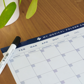 My Medical Folder included medical calendar planner with dry erase marker displayed on a wooden desk.