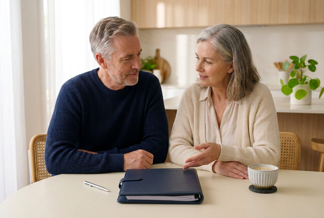 Couple sitting together at a kitchen table with a navy medical folder.
