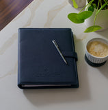 Navy My Medical Folder medical organiser on a marble tabletop beside a coffee and plant, designed to organise medical records, appointments and important health documents.