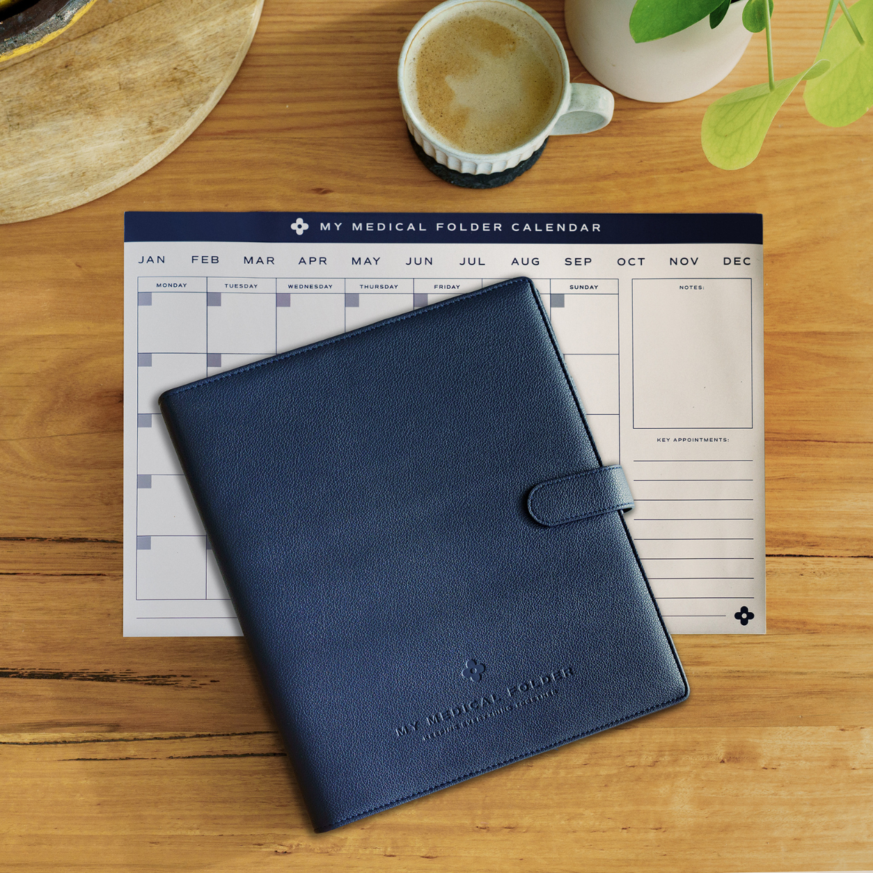 My Medical Folder and magnetic monthly health planner displayed together on a wooden table with a coffee cup